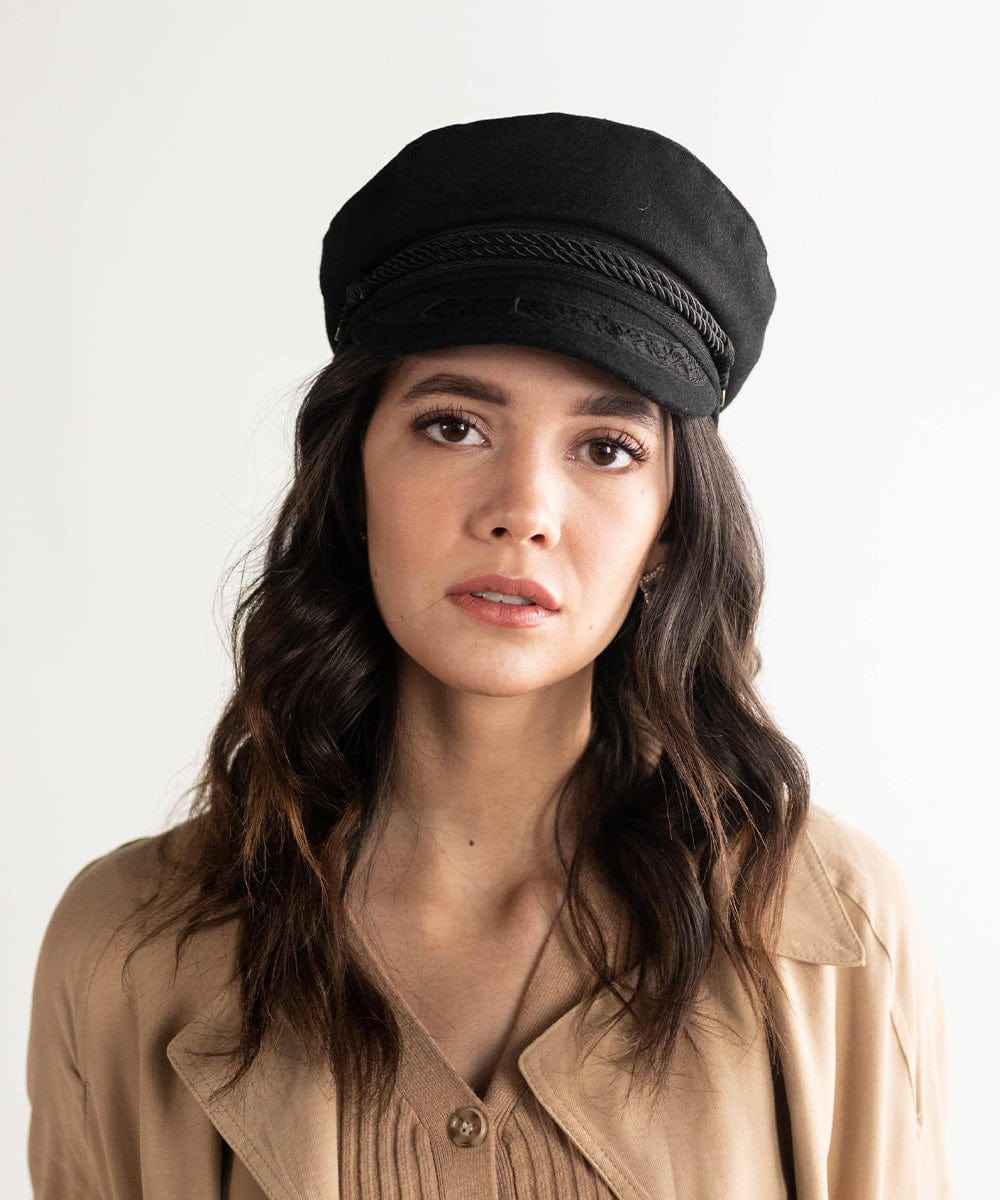 Woman wearing a black lieutenant cap and a beige jacket against a plain background #color_black