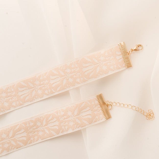 Close up image of a white printed hat band with a gold chain and hook on the ends on a plain background #color_white