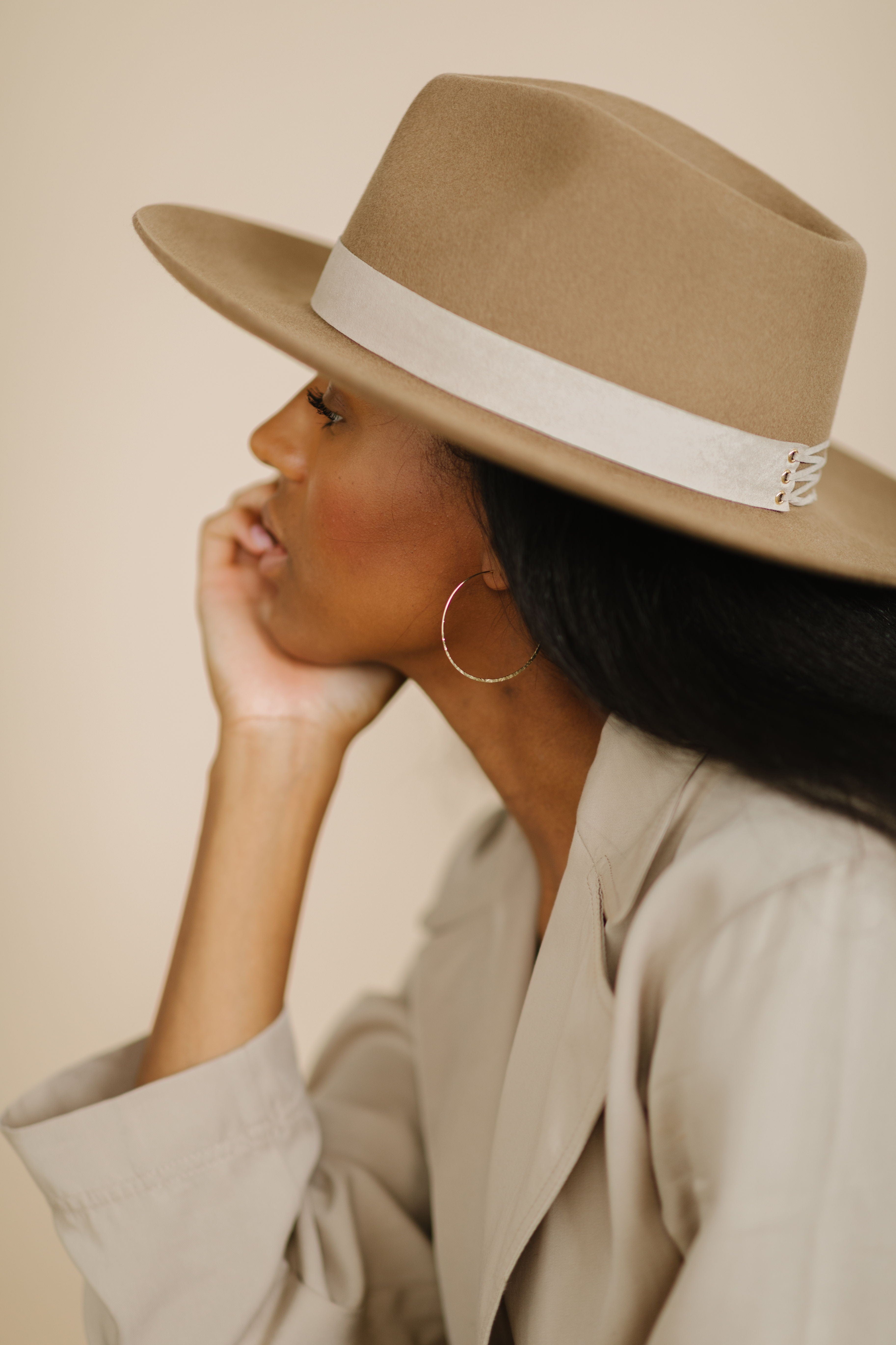 Woman wearing a brown hat with a taupe corset band and a beige shirt, facing sideways against a plain background #color_taupe
