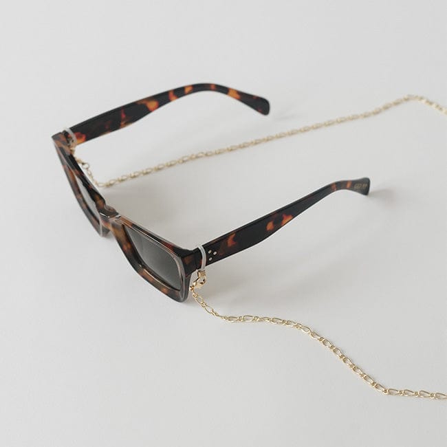 Sunglasses with tortoiseshell frame and gold chain strap on a plain background #color_gold