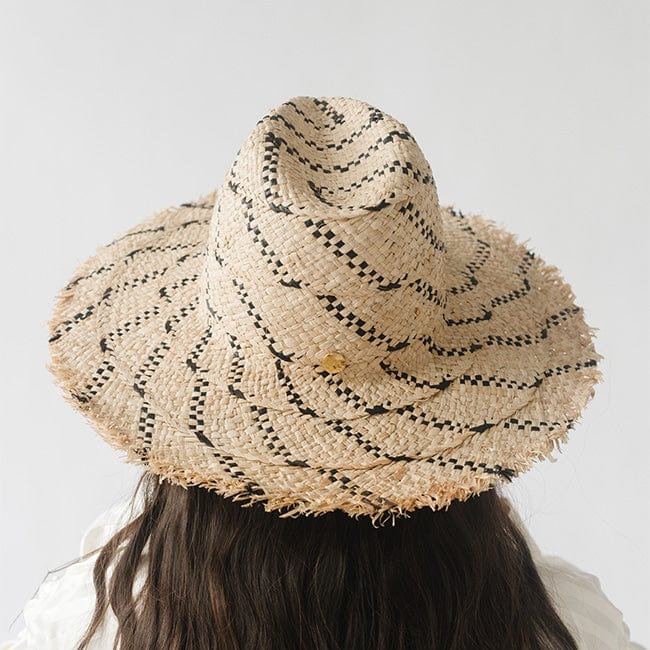 Woman wearing a natural colored straw hat with black patterns, facing behind against a plain background #color_natural/black