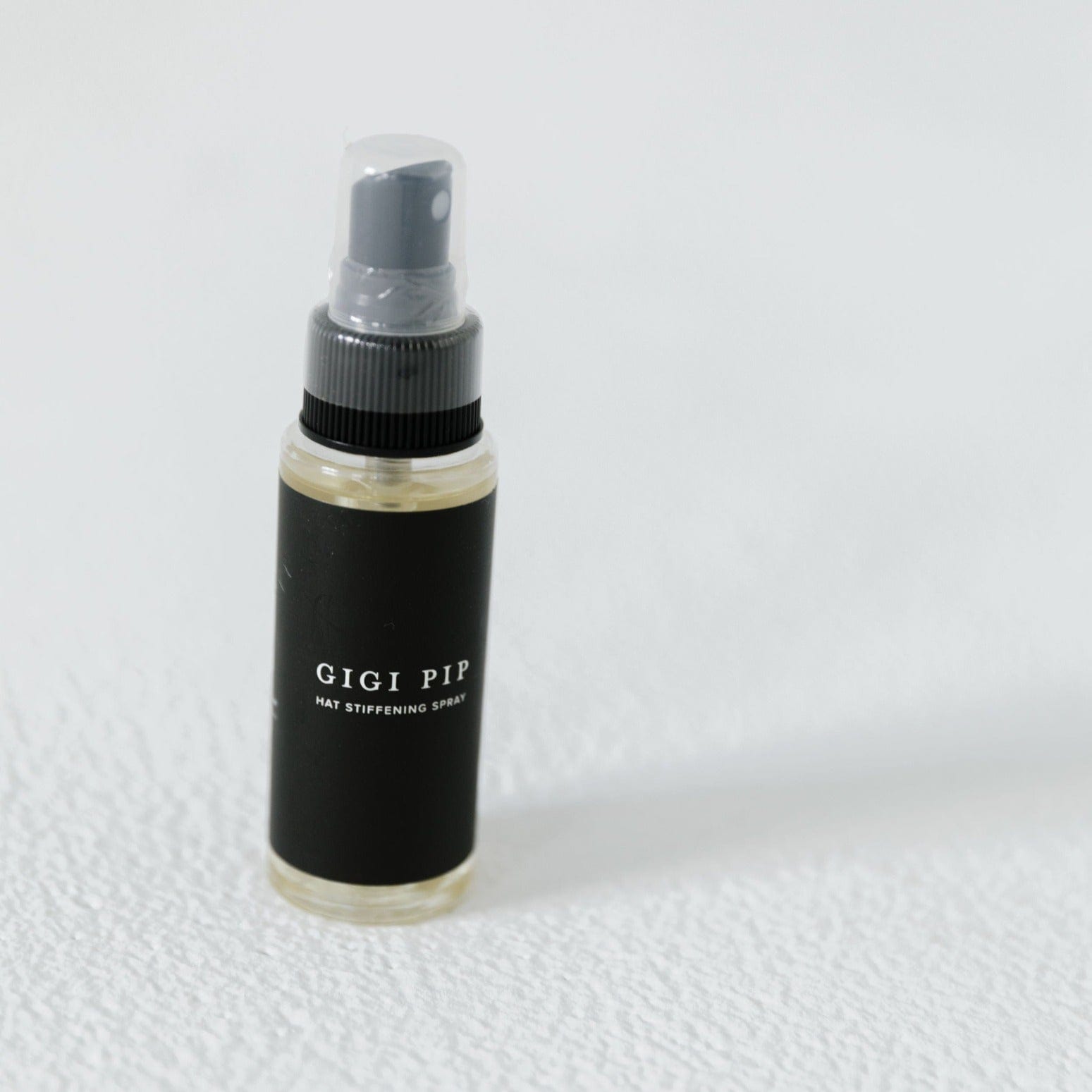 A hat stiffening spray with the brand label 'GIGI PIP' on a plain background #color_black