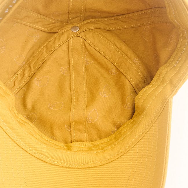 The inside of a mustard colored ball cap on a plain background #color_mustard