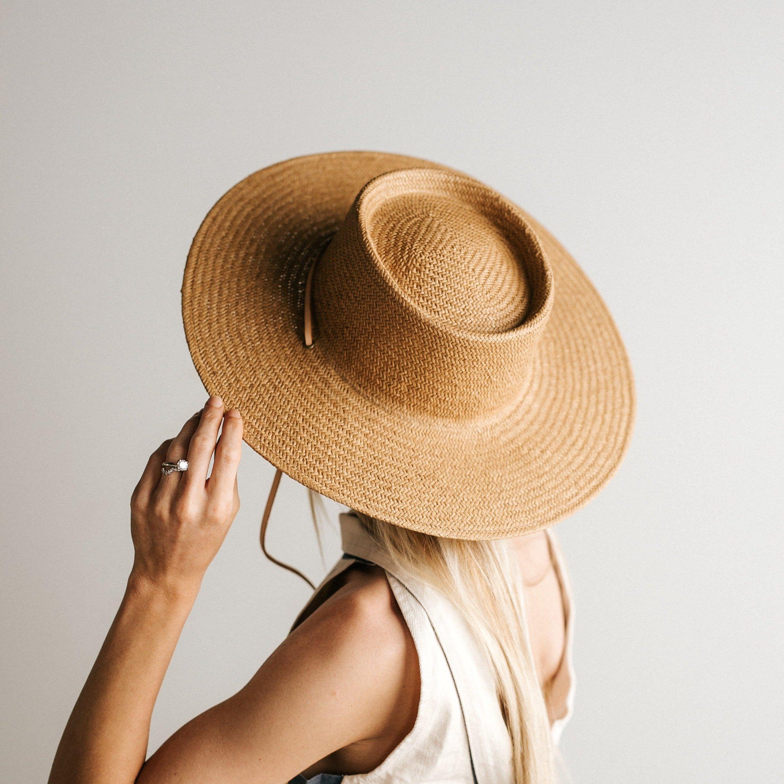 Woman wearing a natural colored straw hat with a band facing behind against a plain background #color_natural