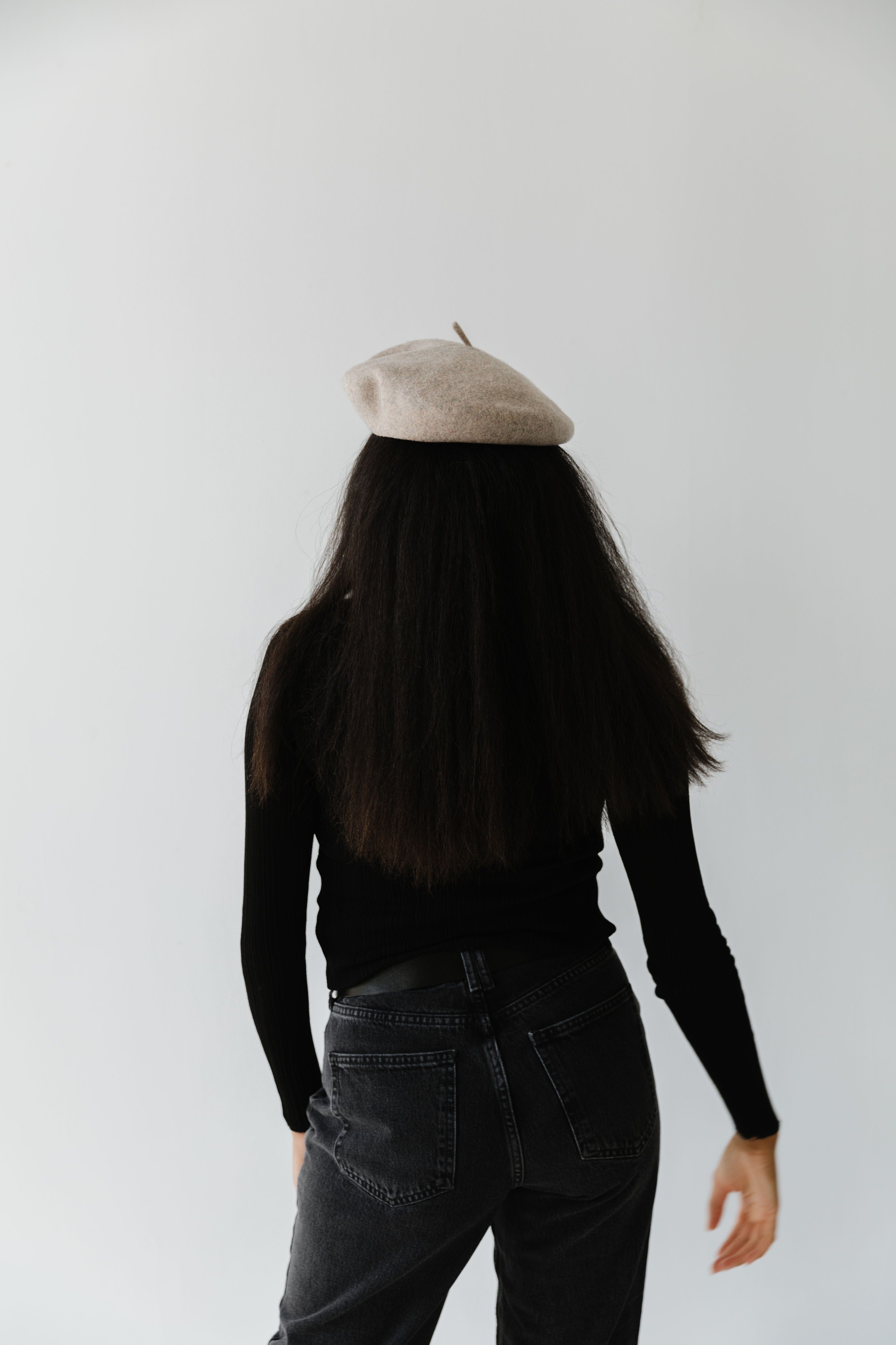 Woman wearing a taupe beret, black t-shirt and jeans against a plain background #color_taupe