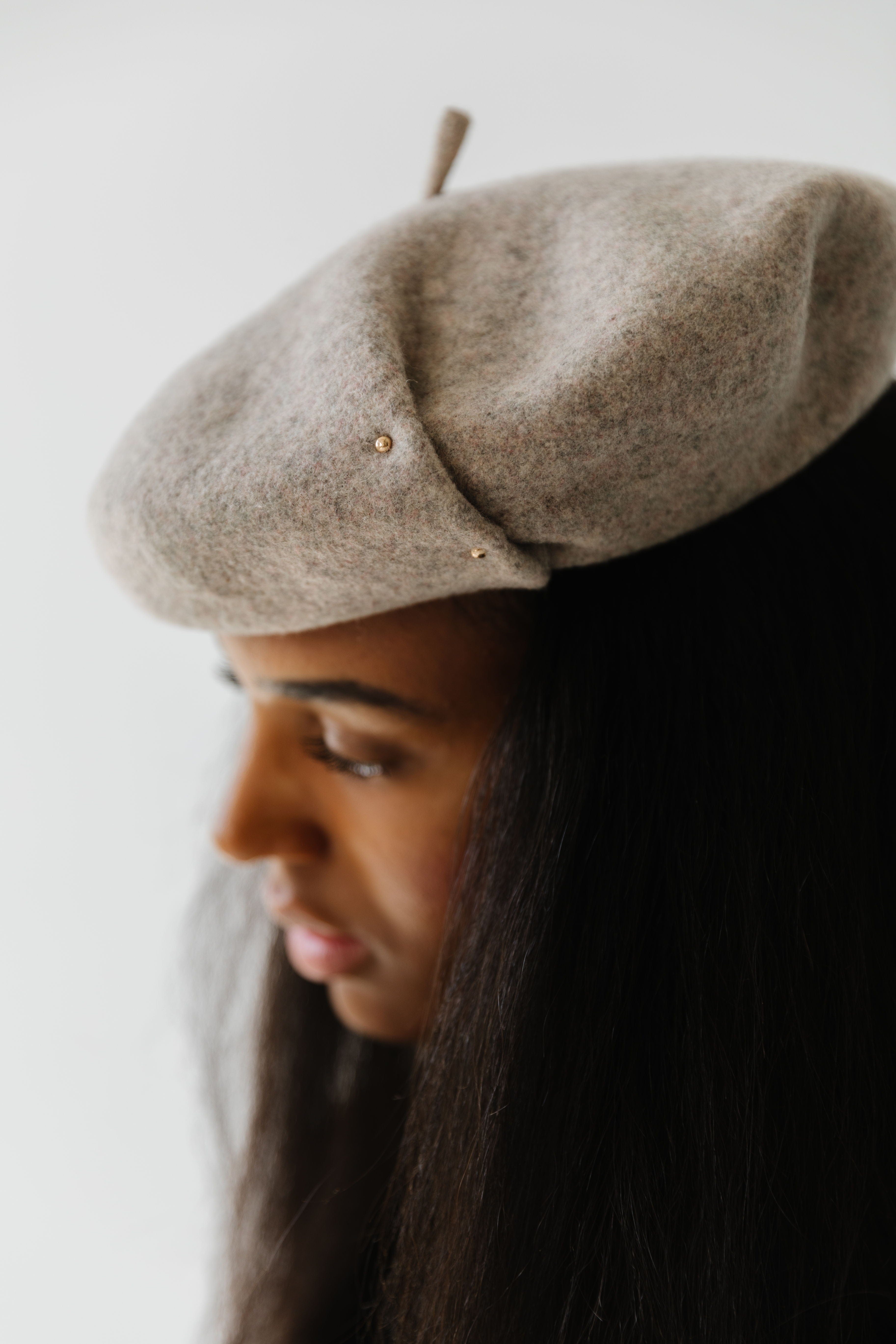 Woman wearing a taupe beret facing sideways against a plain background #color_taupe