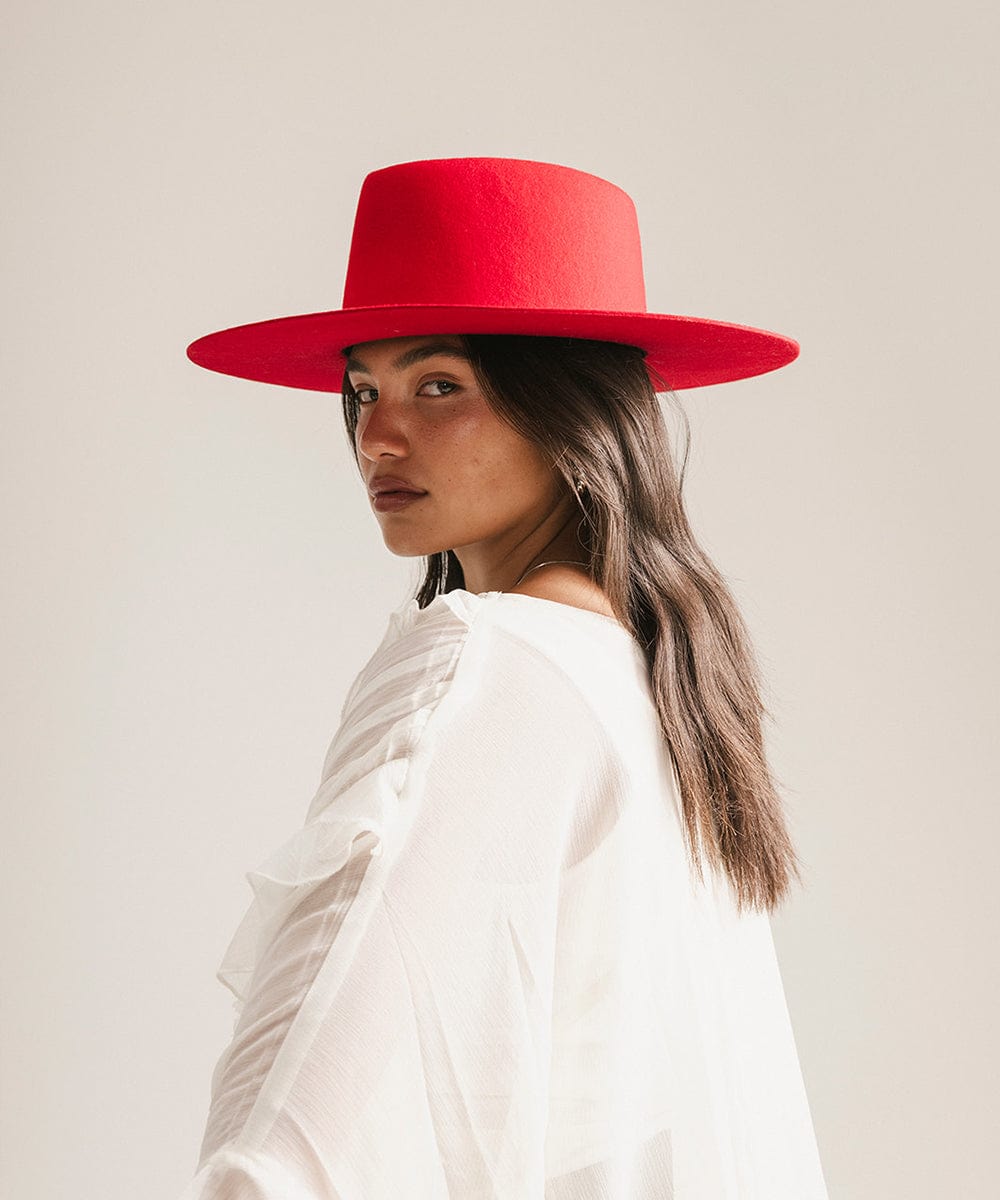 Woman wearing a cherry red felt hat and a white shirt, posing against a plain background #color_cherry red