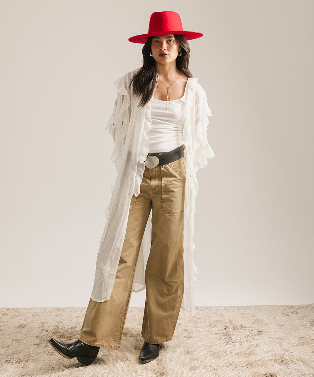 Woman wearing a cherry red felt hat, a white top with a white shirt, beige pants, and black shoes against a plain background #color_cherry red