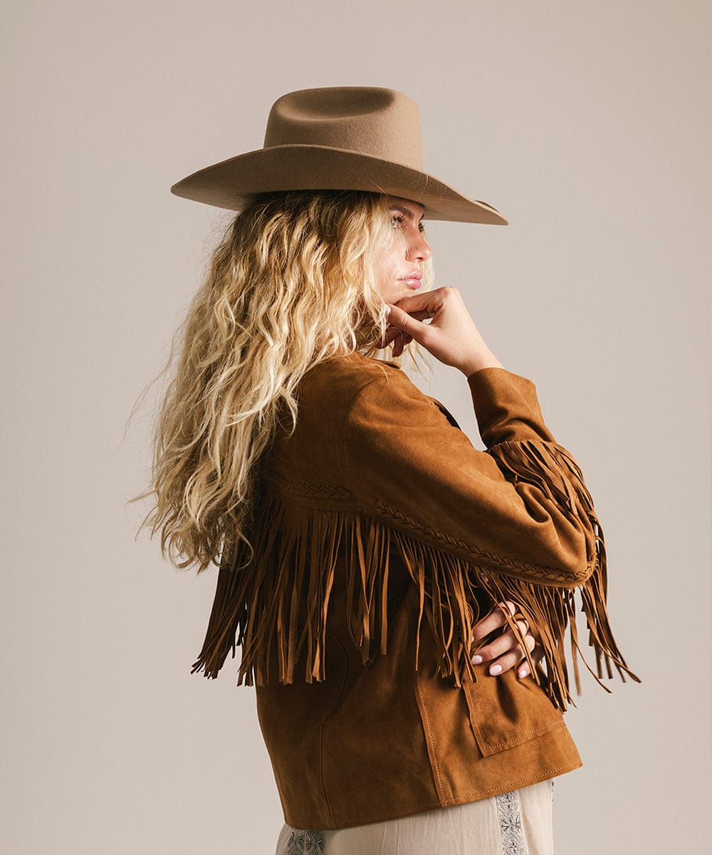Woman wearing a brown cowboy hat and a brown jacket, facing sideways against a plain background #color_brown