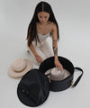 Gigi Pip hat carrying totes for women - Hat Travel Case 2.0 - 100% tarpaulin round shell with a 100% polyester lining to carry 1-3 of your hats safely, featuring a trolley pass on the back of the case, a carrying handle + a shoulder sling [black]