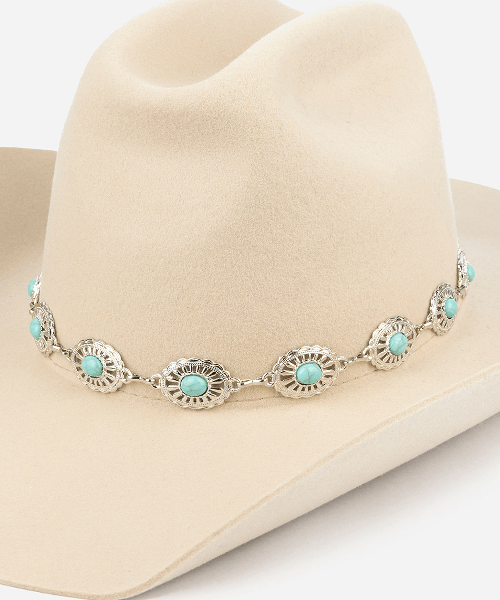 Cowboy hat with a silver and turquoise concho hat band against a plain background #color_silver