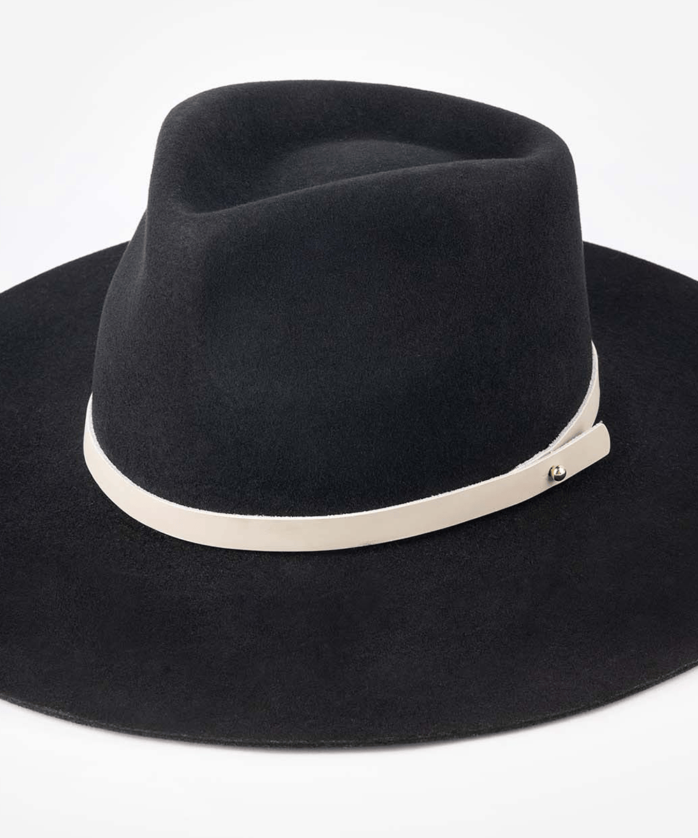 Black felt wide-brim fedora hat with a light beige band and a small gold-tone metal accent, shown against a plain white background #color_stone