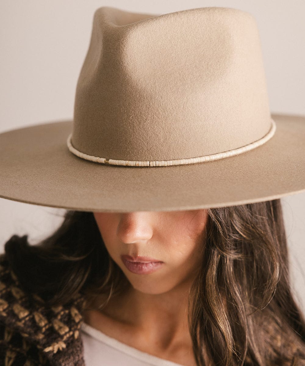 Close-up of a person wearing a beige hat with a neutral background #color_natural fossil