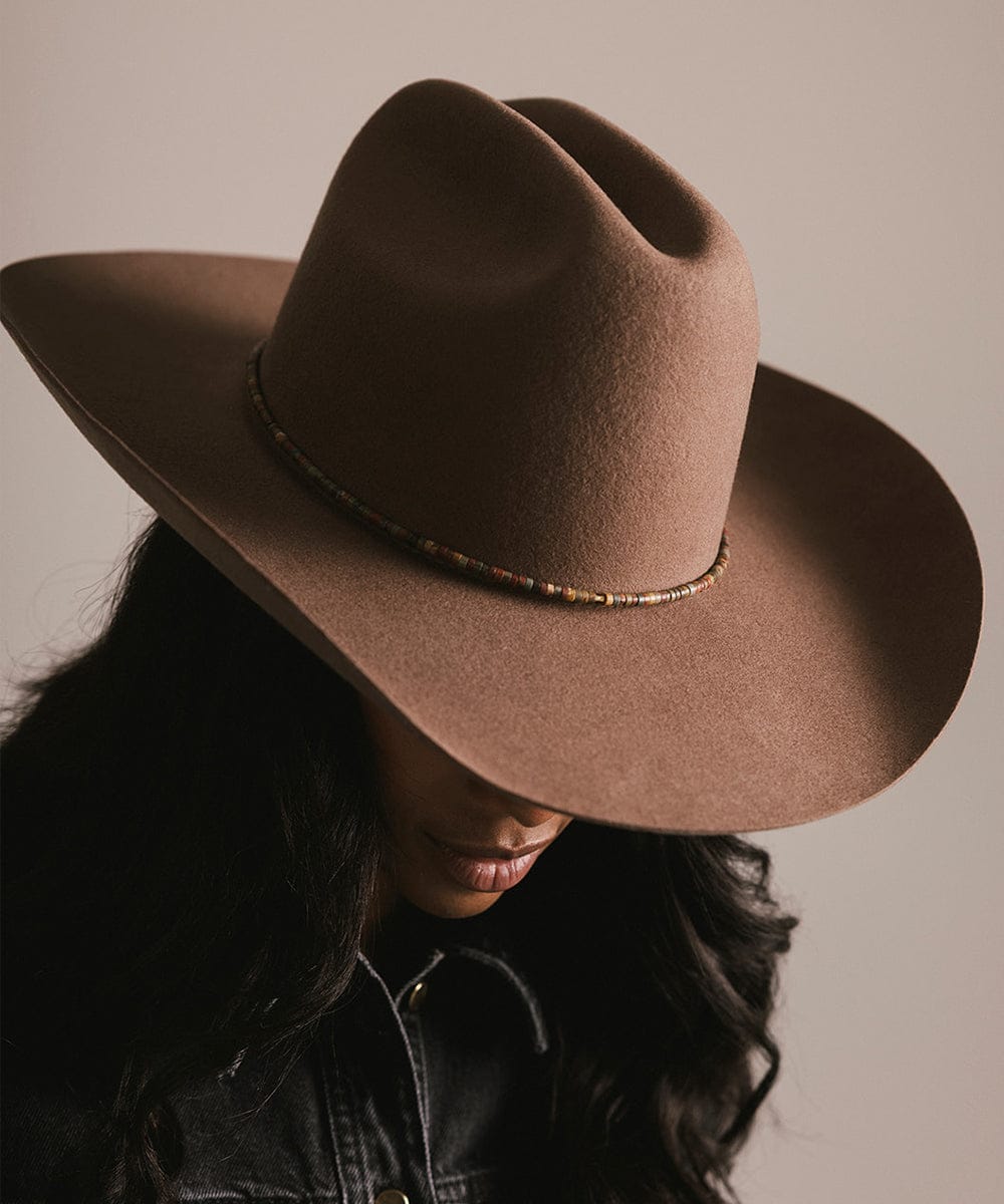 Person wearing a brown cowboy hat against a neutral background #color_brown jasper