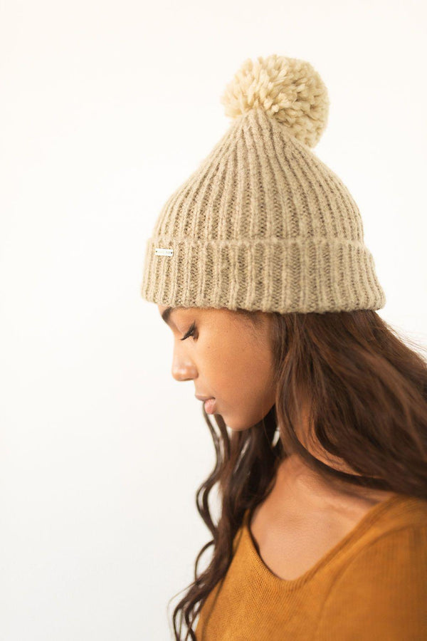 Gigi Pip beanies for women - Mo Pom Beanie - classic knit beanie with a pom on the crown, featuring the Gigi Pip logo on a metal bar on the front fold [latte]