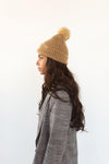 Gigi Pip beanies for women - Mo Pom Beanie - classic knit beanie with a pom on the crown, featuring the Gigi Pip logo on a metal bar on the front fold [tan]