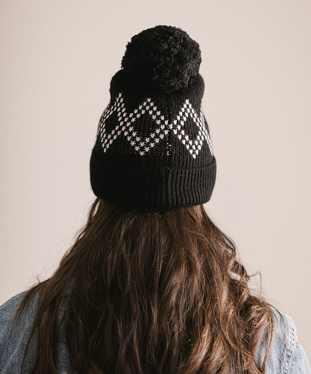 Person wearing a black knit beanie with a pattern on a neutral background #color_black