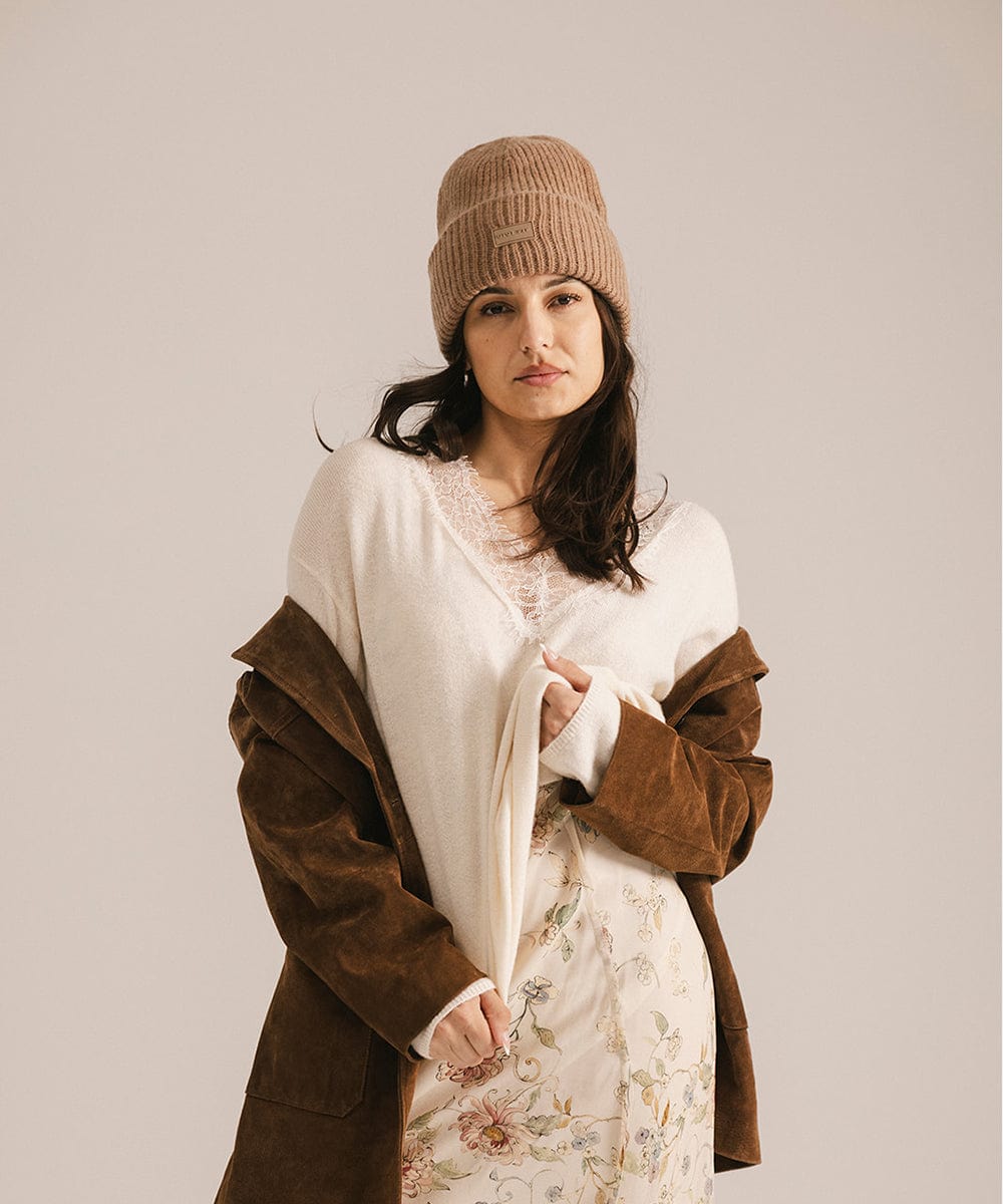 Woman wearing a brown coat and brown beanie against a plain background #color_brown