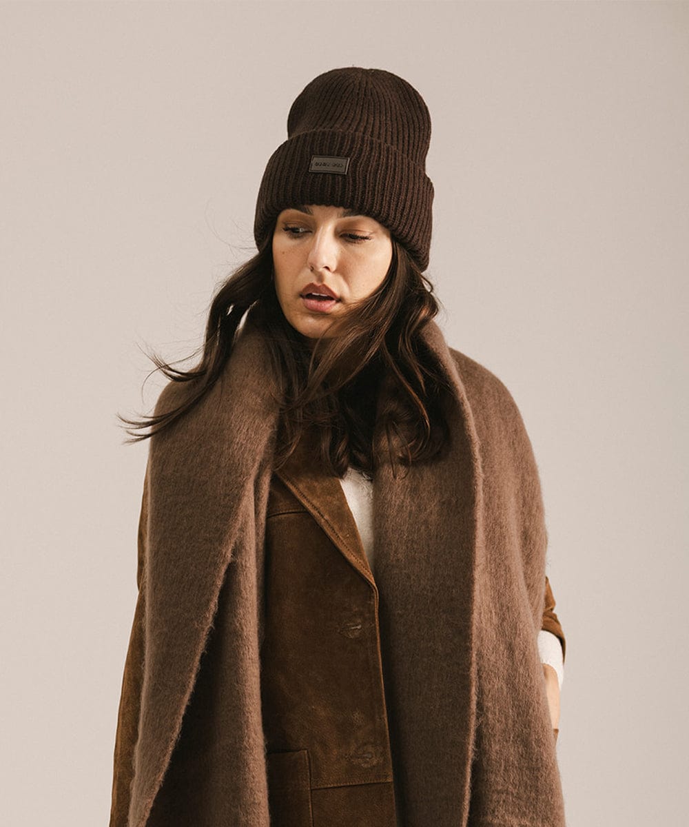 Woman wearing a brown coat and a dark brown beanie against a plain background #color_dark brown