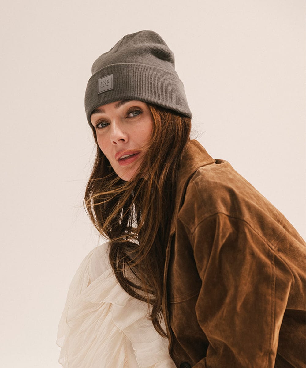 Woman wearing a grey beanie and brown jacket against a plain background #color_grey