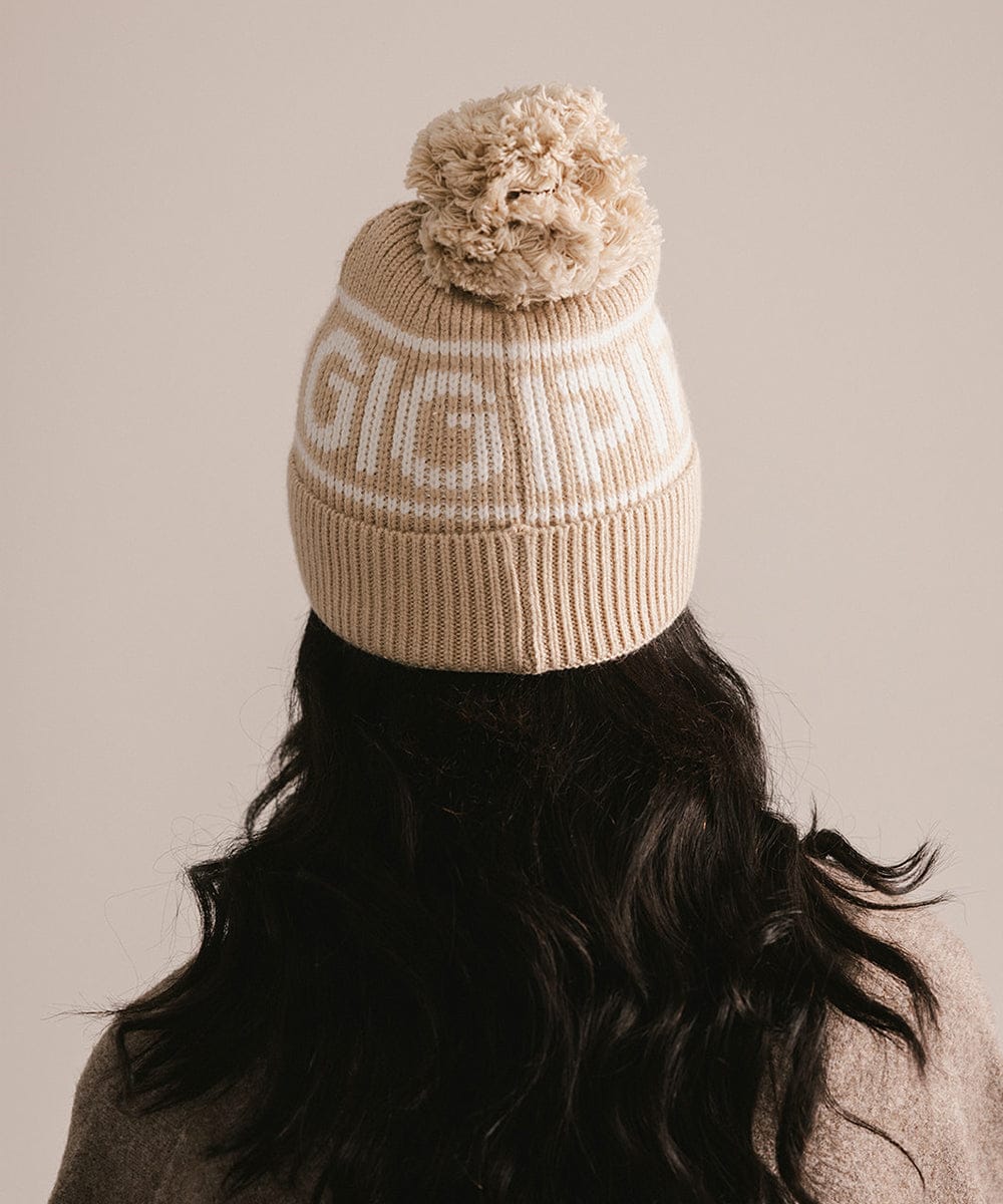 Beige knit beanie with pom-pom worn by a person on a beige background #color_taupe