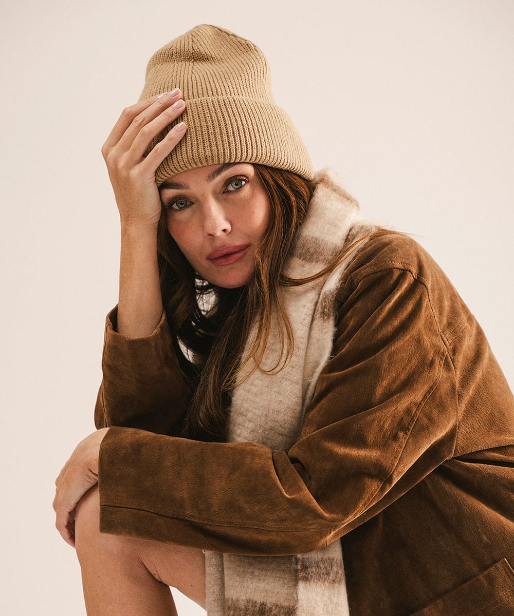 Woman wearing a brown beanie and coat against a beige background #color_tan