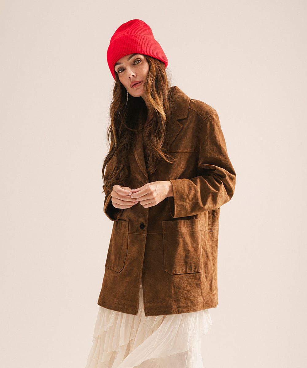 Woman wearing a brown coat and red beanie against a plain background #color_red
