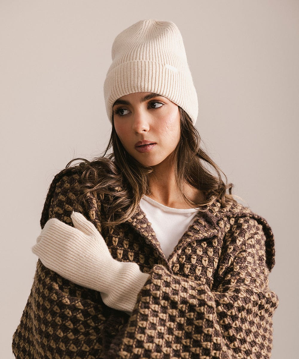 Woman wearing a patterned coat, white beanie, and gloves against a neutral background #color_taupe