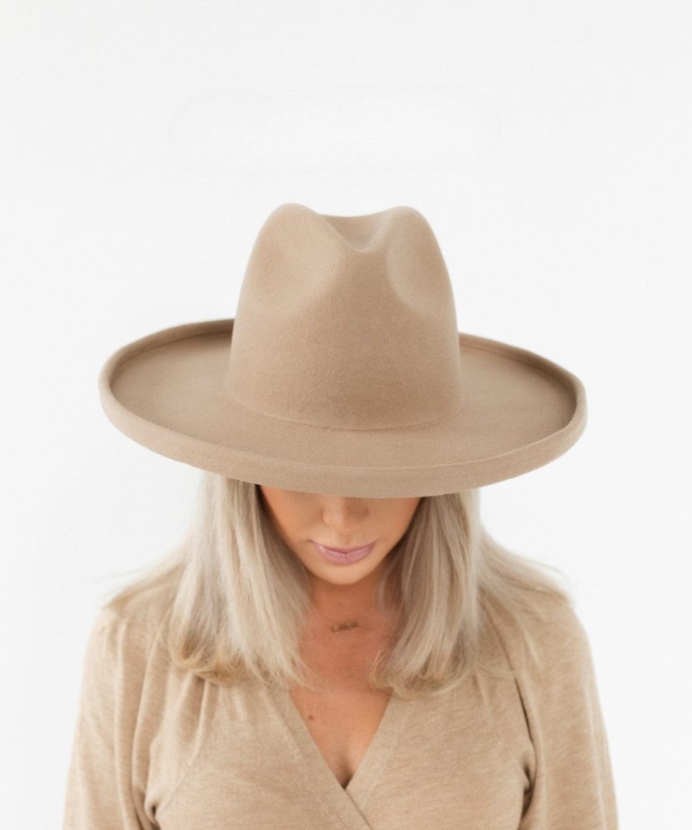 Woman wearing a tan pencil brim felt hat and a beige shirt against a plain background #color_tan