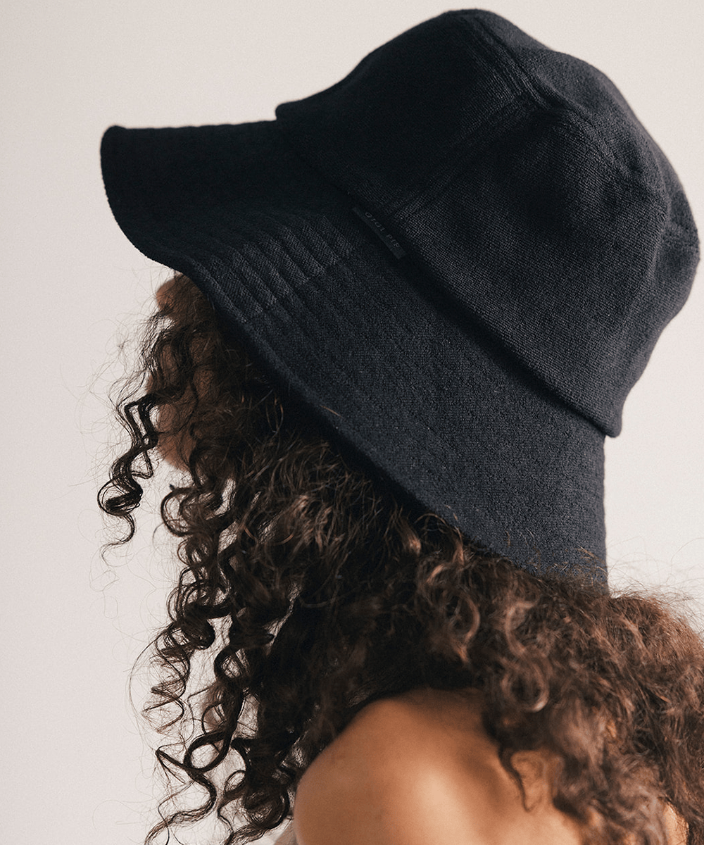 Woman wearing a black bucket hat against a plain background #color_black