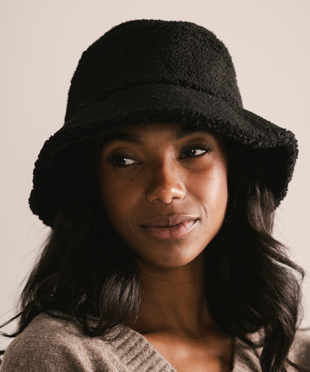 Woman wearing a black sherpa bucket hat against a neutral background #color_black