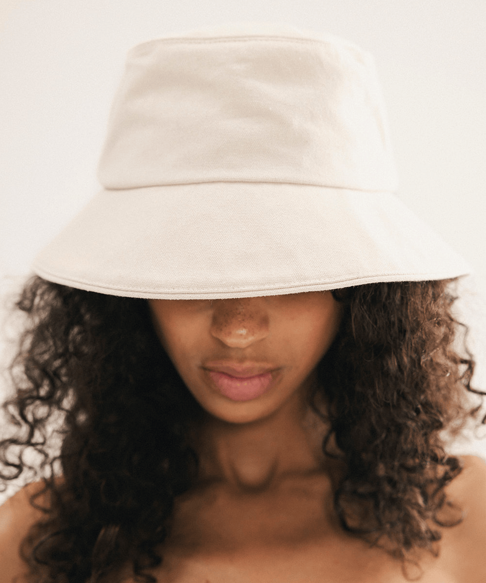 Woman wearing a cream bucket hat with a plain background #color_cream