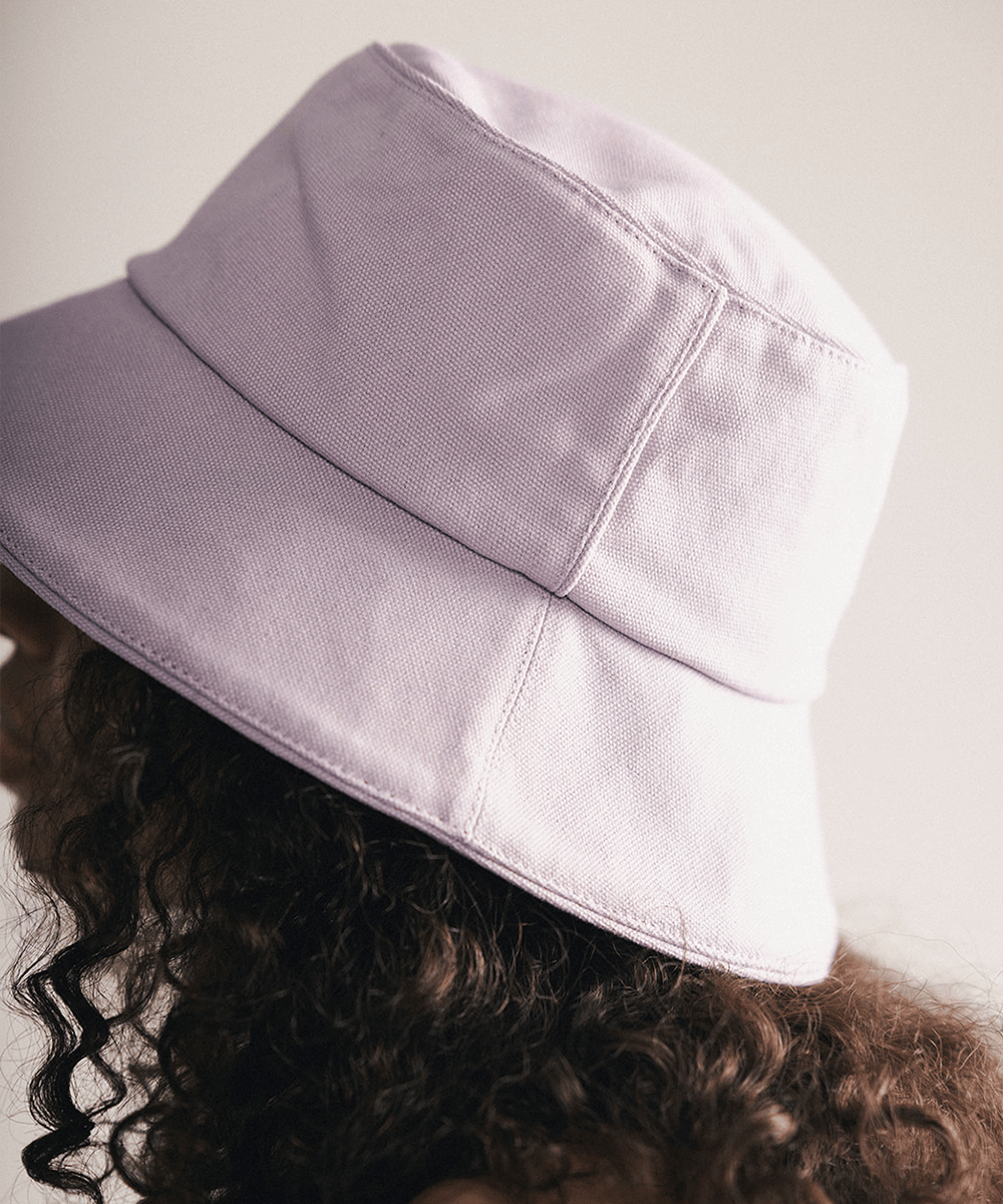 Woman wearing a lavender bucket hat with a plain background #color_lavender