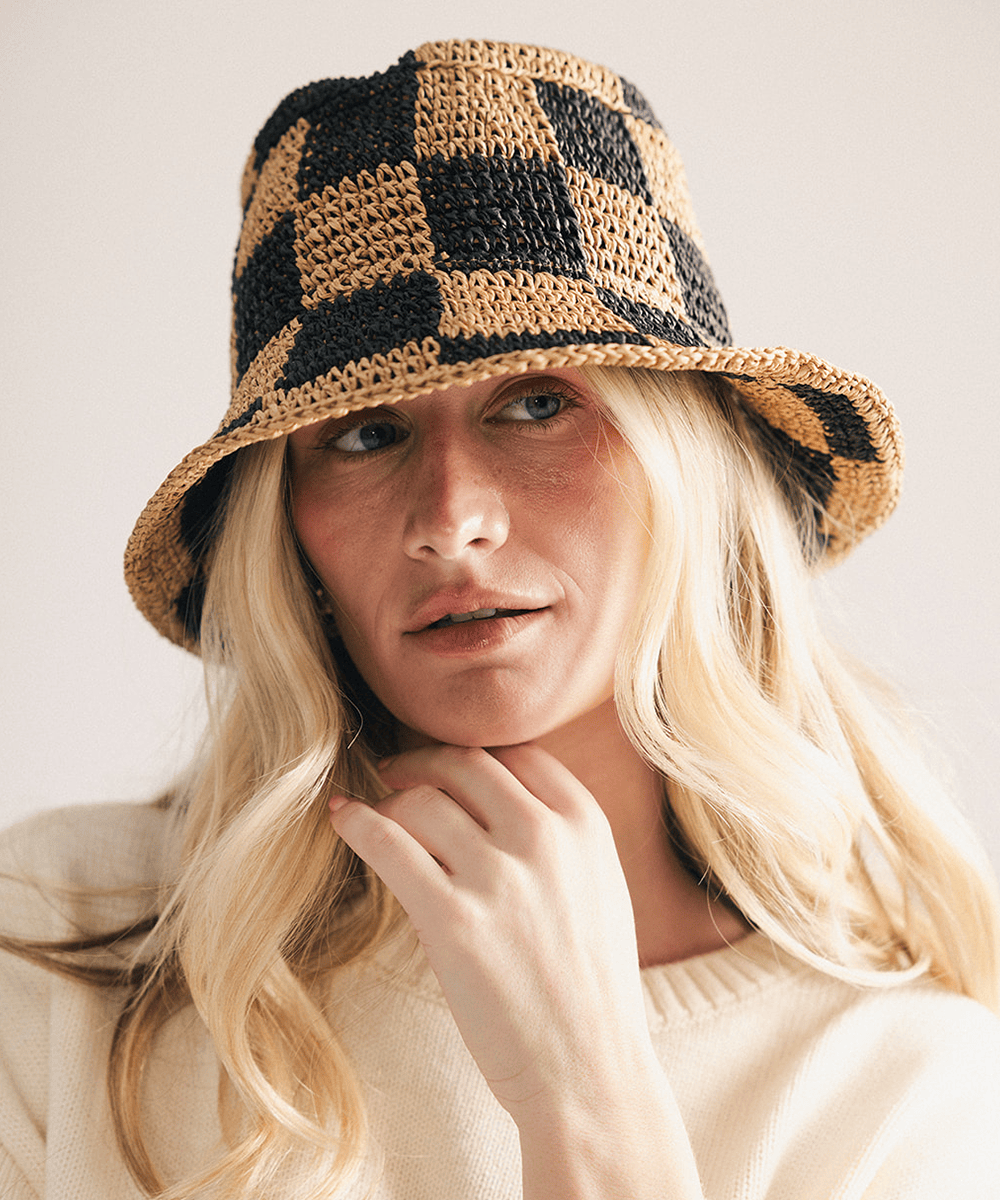 Woman wearing a black checkered crochet packable bucket hat made from paper straw, displayed against a white background. #color_black check