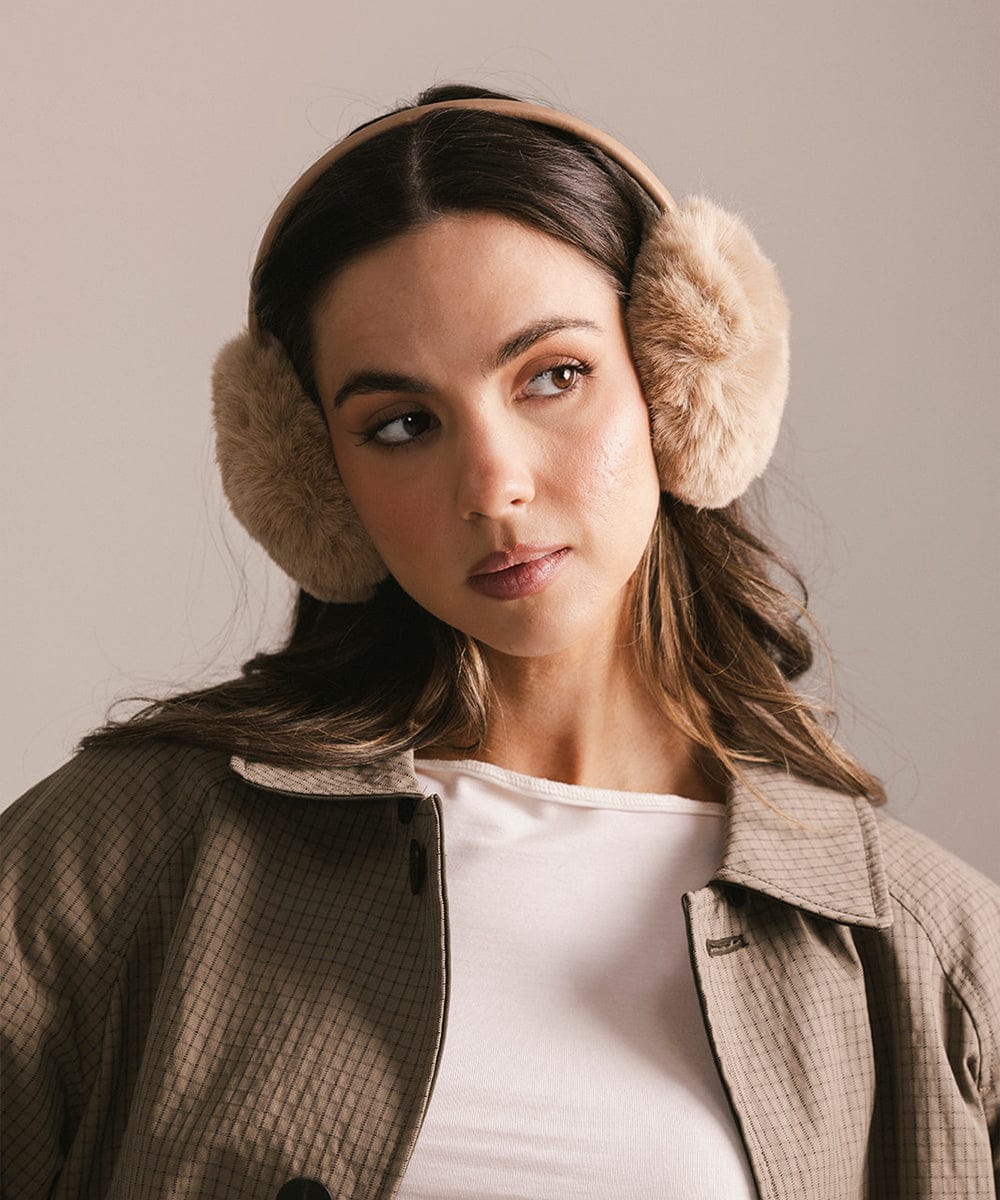 Woman wearing beige earmuffs against a plain background #color_tan