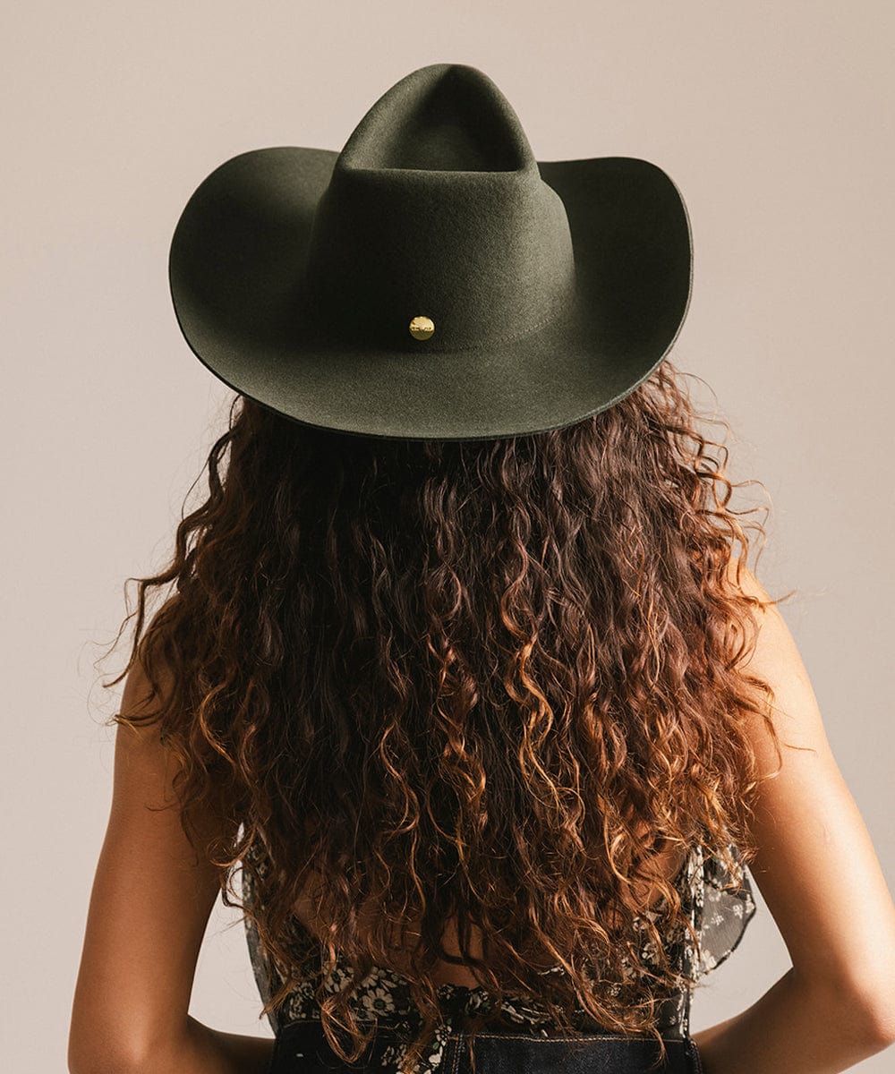 Person wearing a green cowboy hat with a neutral background #color_dark green