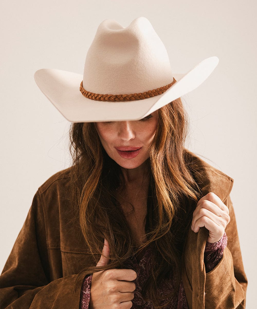 Woman wearing a beige cowboy hat and brown jacket against a plain background #color_cream