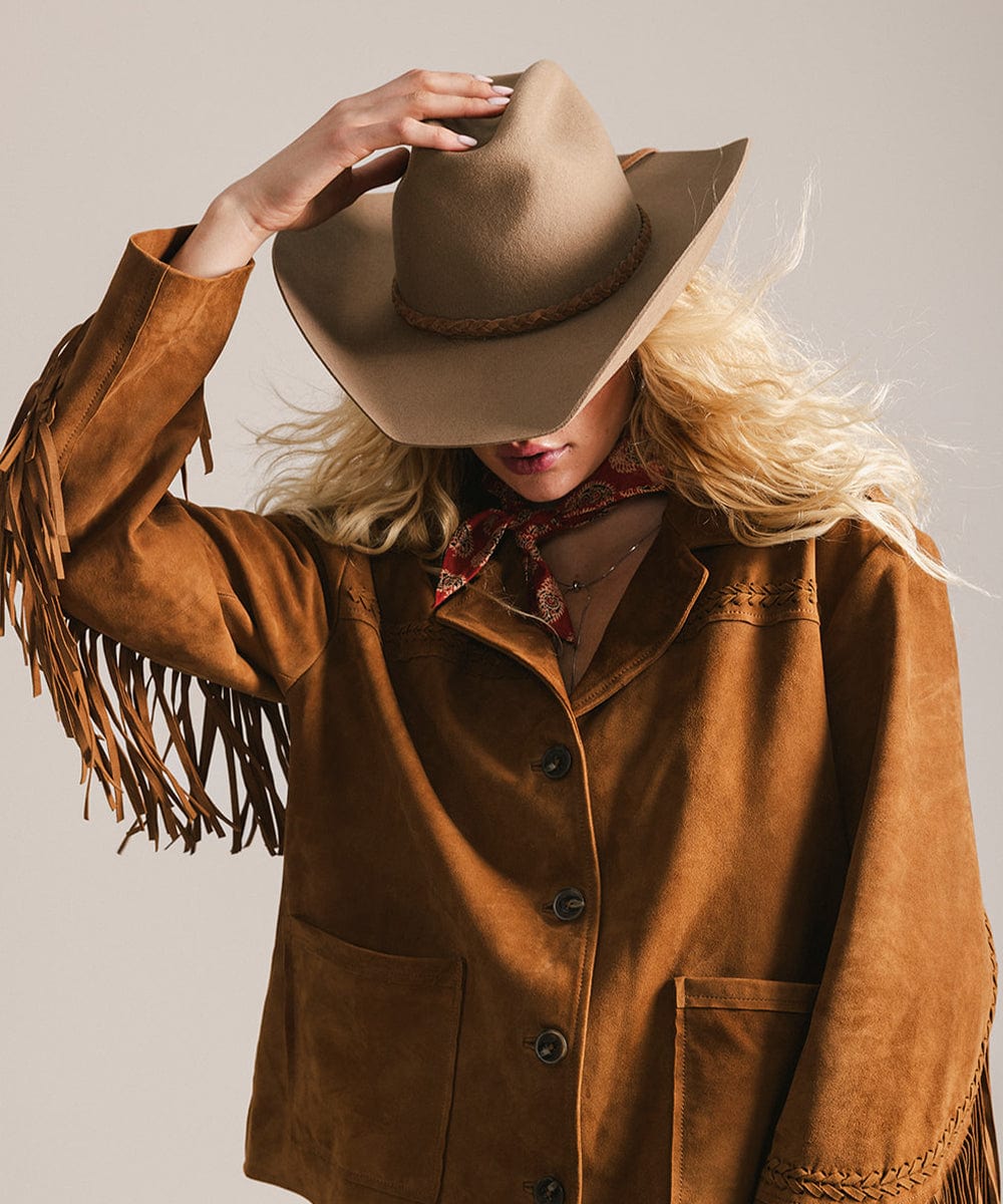 Person wearing a brown fringed jacket and cowboy hat against a neutral background #color_brown