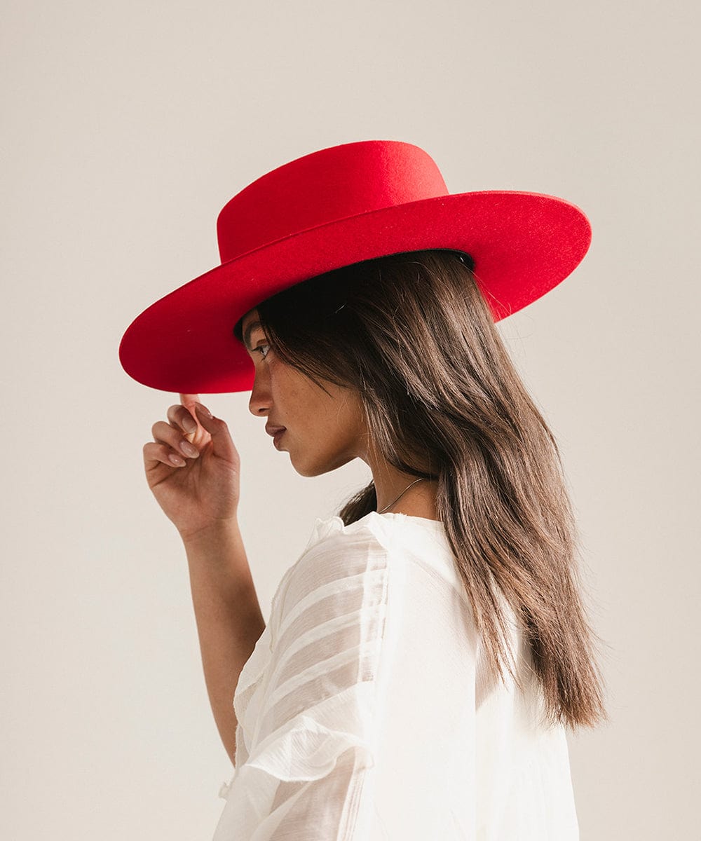 Woman wearing a cherry red felt hat and a white shirt, facing sideways against a plain background #color_cherry red