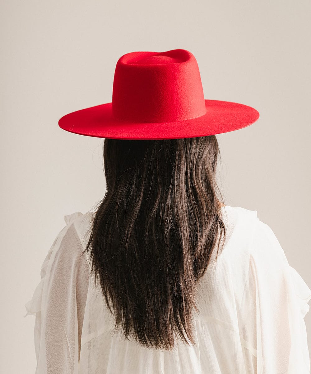 Woman wearing a cherry red felt hat and a white shirt, facing behind against a plain background #color_cherry red