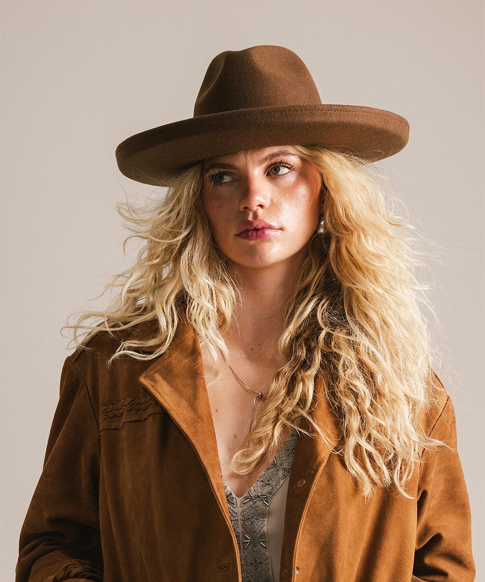 Woman wearing a chocolate colored pencil brim felt fedora hat and a brown coat against a plain background #color_chocolate