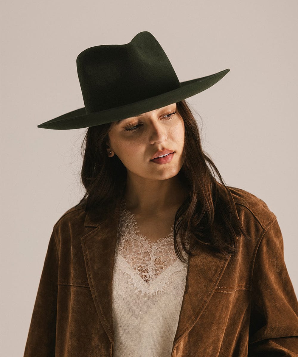 Woman wearing a dark green hat and brown jacket against a plain background #color_dark green