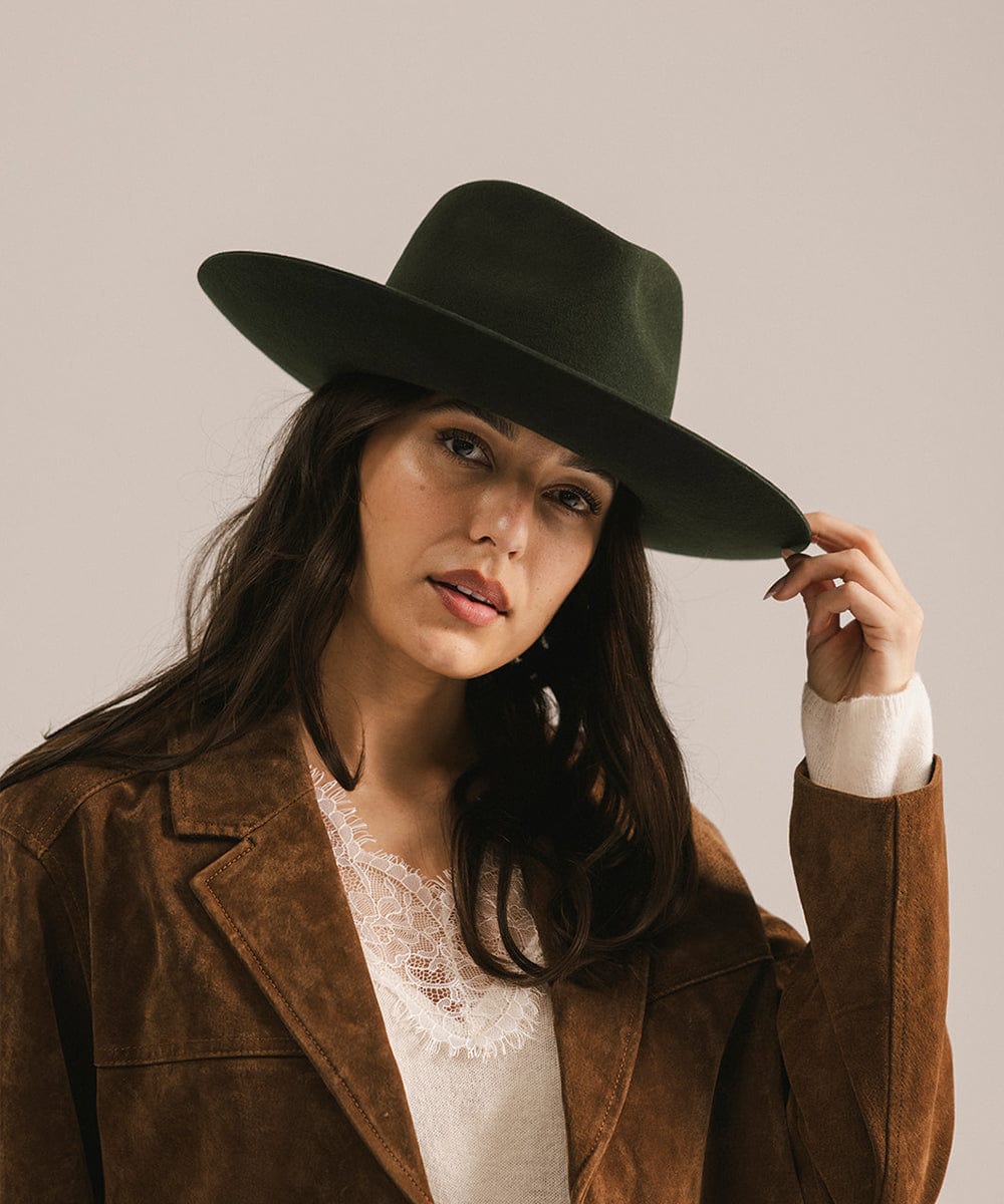 Woman wearing a dark green hat and brown coat against a plain background #color_dark green