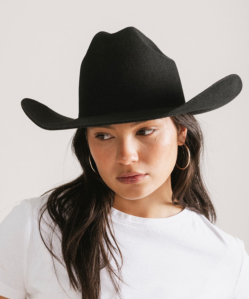 Woman wearing a black cowboy hat and a white t-shirt against a plain background #color_black