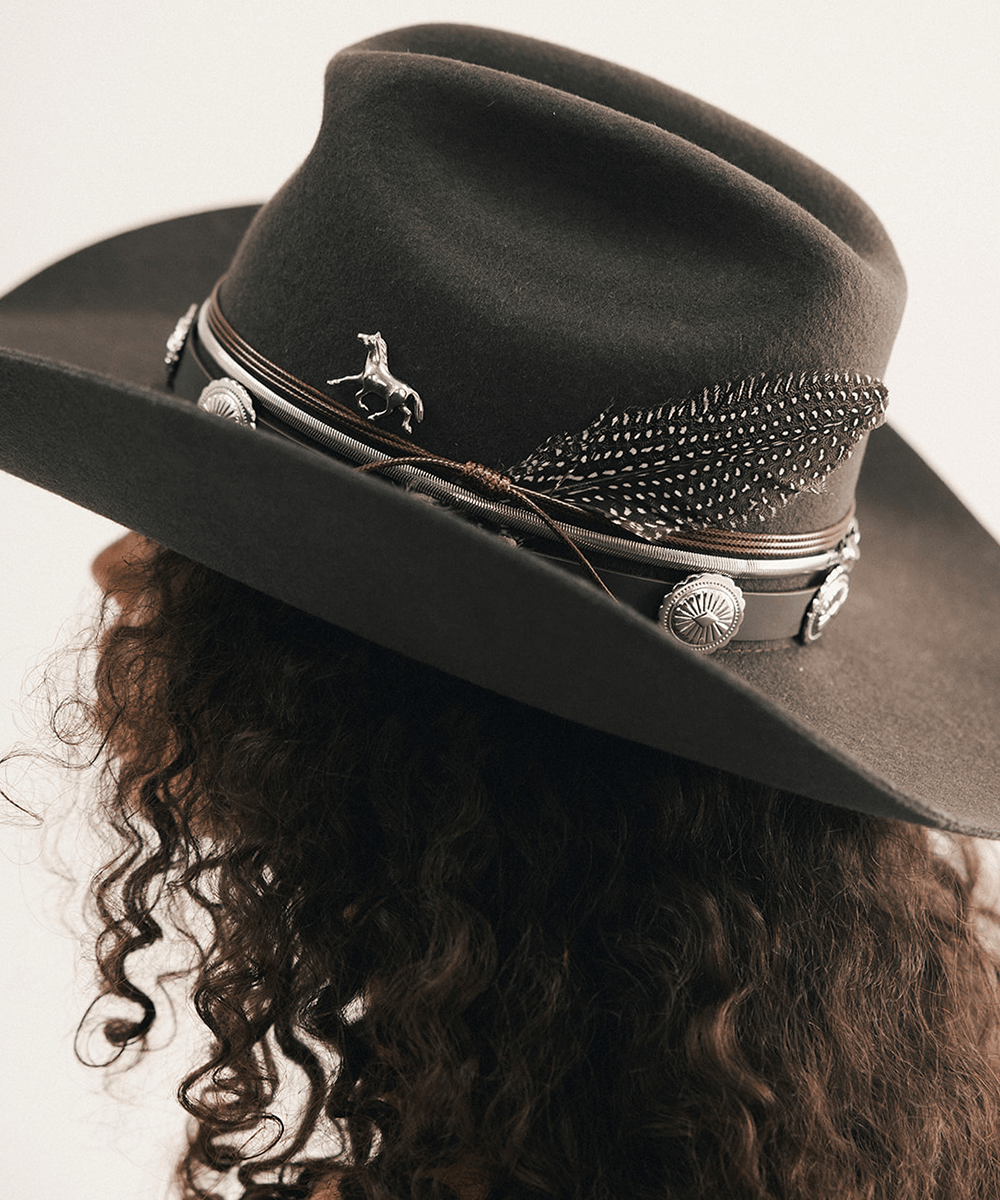 Woman wearing a cowboy hat and strapless denim dress against a plain background #color_dark brown
