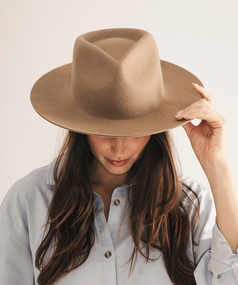 Woman wearing a brown fedora hat with a neutral background #color_brown