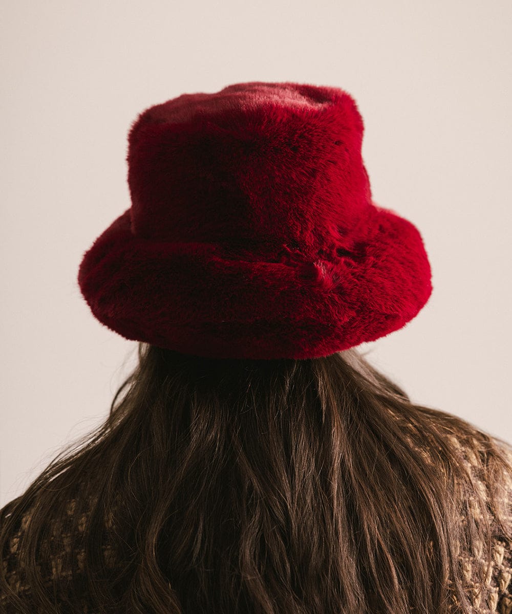 Red fuzzy hat worn by a person with a neutral background #color_burgundy