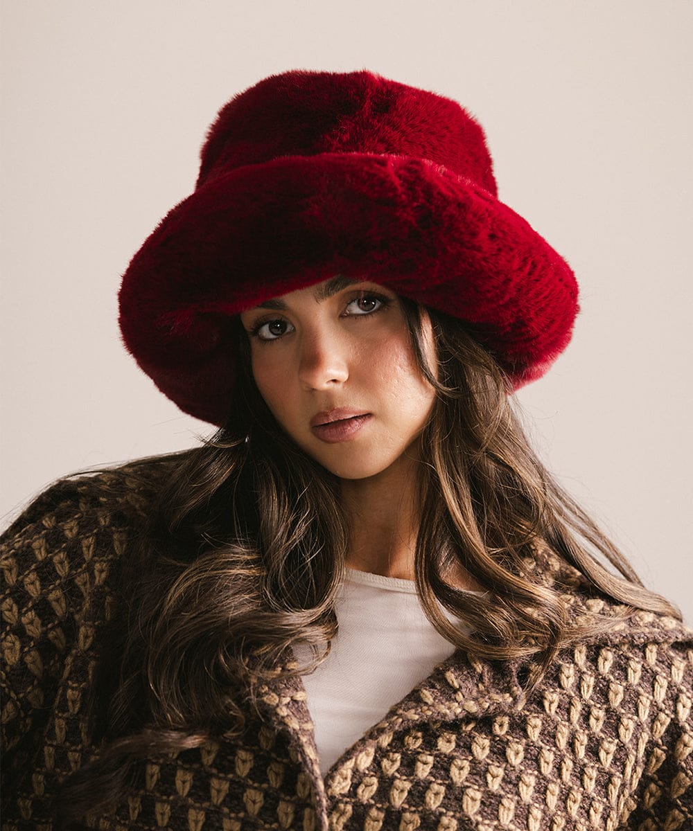 Woman wearing a red fur hat and patterned coat against a neutral background #color_burgundy