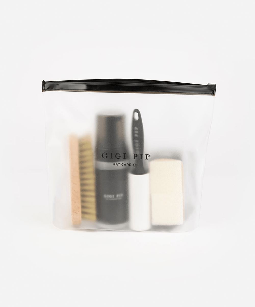 Hat care kit with brush, spray bottle, and other tools in a clear pouch on a white background #color_black