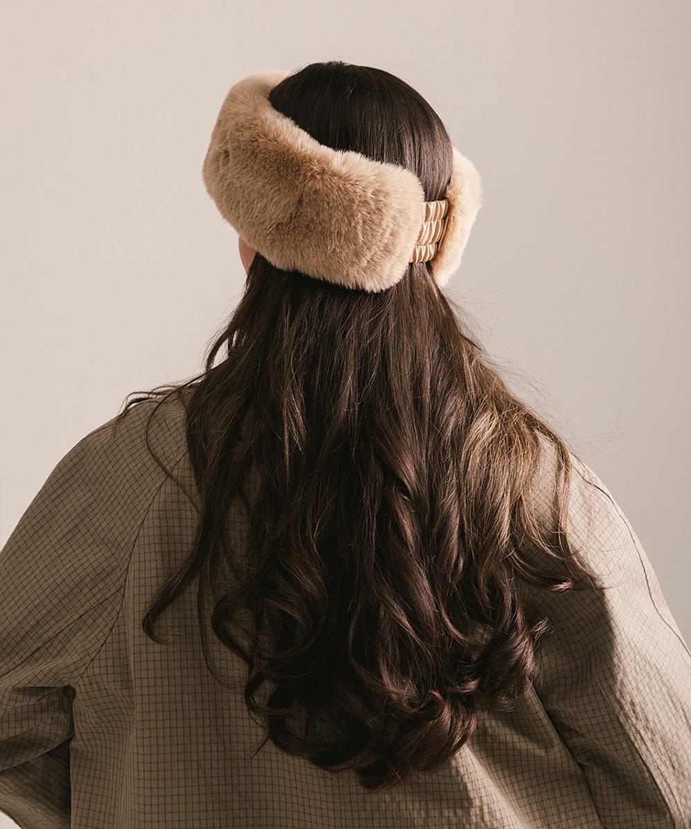 Person wearing a beige fur headband with long dark hair on a neutral background #color_tan